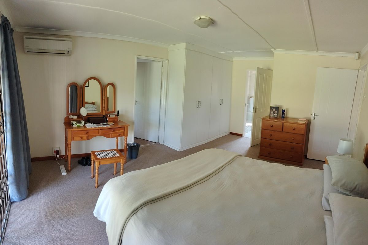 Spacious bedroom featuring built-in cupboards, carpeted flooring, and a wall-mounted split-system air conditioner for climate control.