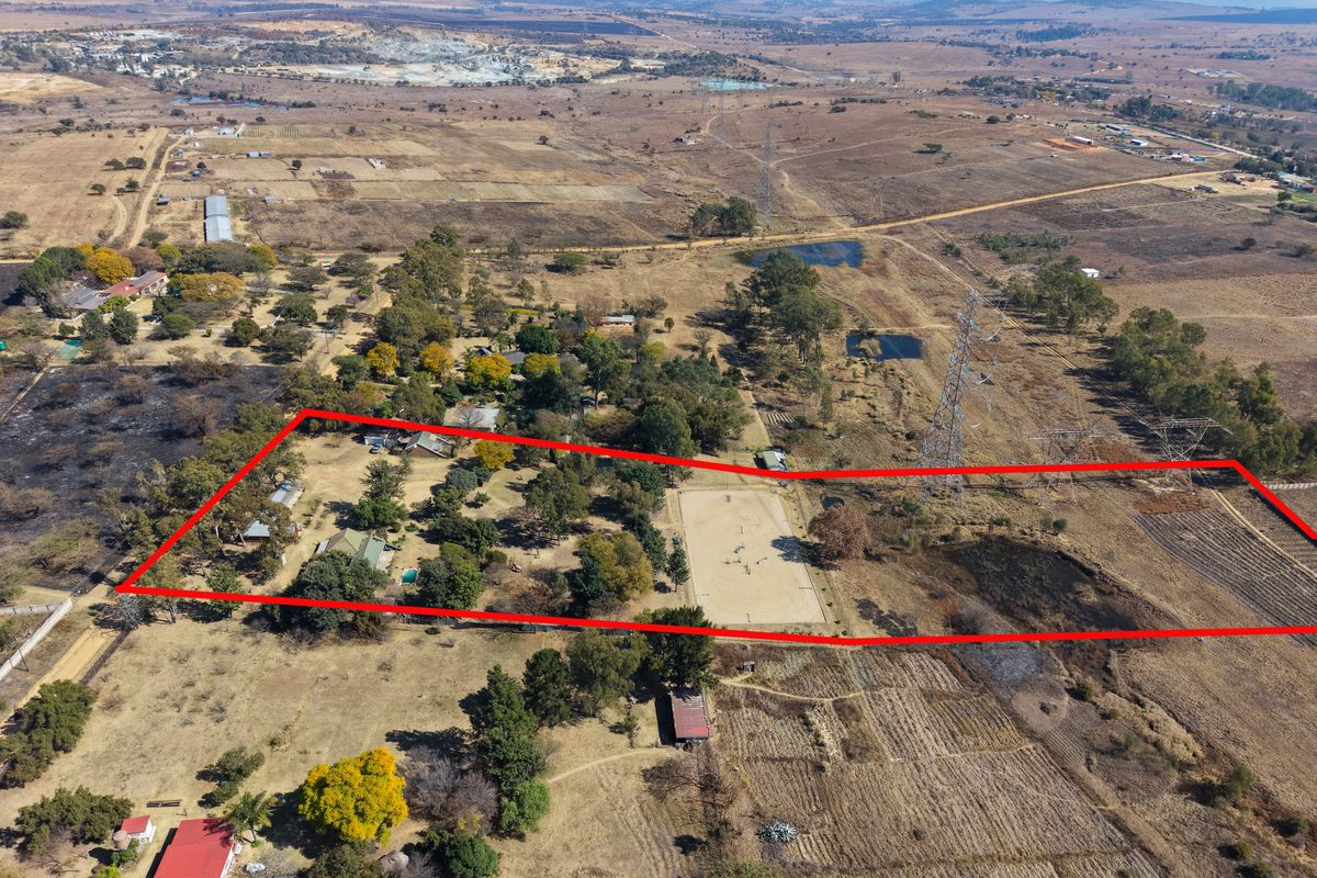 Aerial view of a large rural property featuring an equestrian arena, swimming pool, and multiple outbuildings set within a spacious landscape.