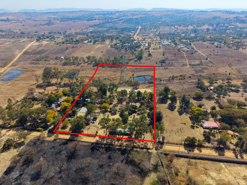 Aerial view of a large rural property plot with mature trees and defined boundary lines, situated in an open landscape.