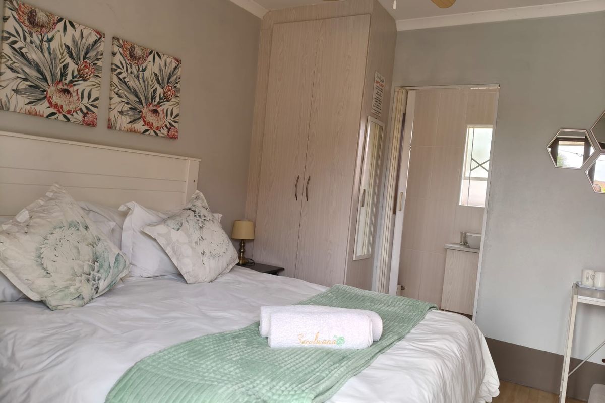 A comfortable bedroom featuring built-in wooden cabinetry and an en-suite bathroom with tiled finishes.