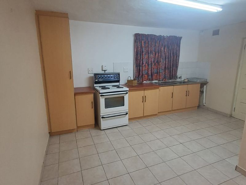A functional kitchen featuring tiled flooring, built-in cabinetry, and a freestanding stove, offering a blank canvas for potential modern updates.