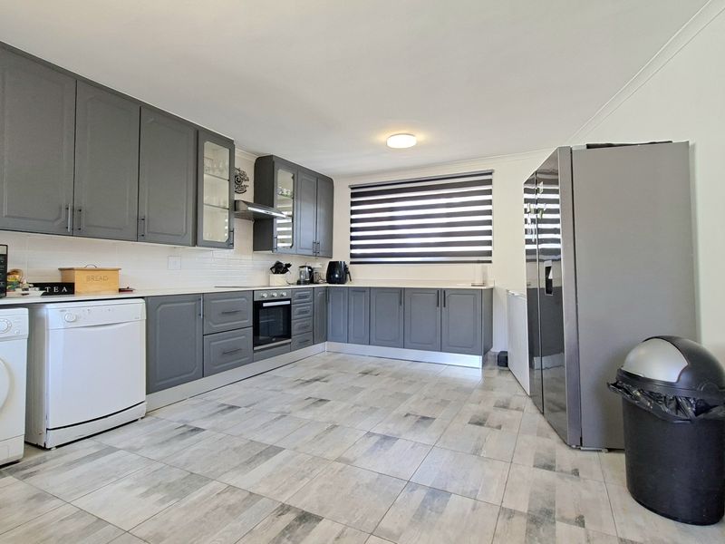 Modern kitchen featuring grey cabinetry, built-in oven, extractor fan, subway tile backsplash, and tiled flooring.
