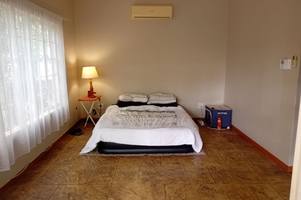A bedroom featuring tiled flooring and a wall-mounted split-system air conditioning unit.