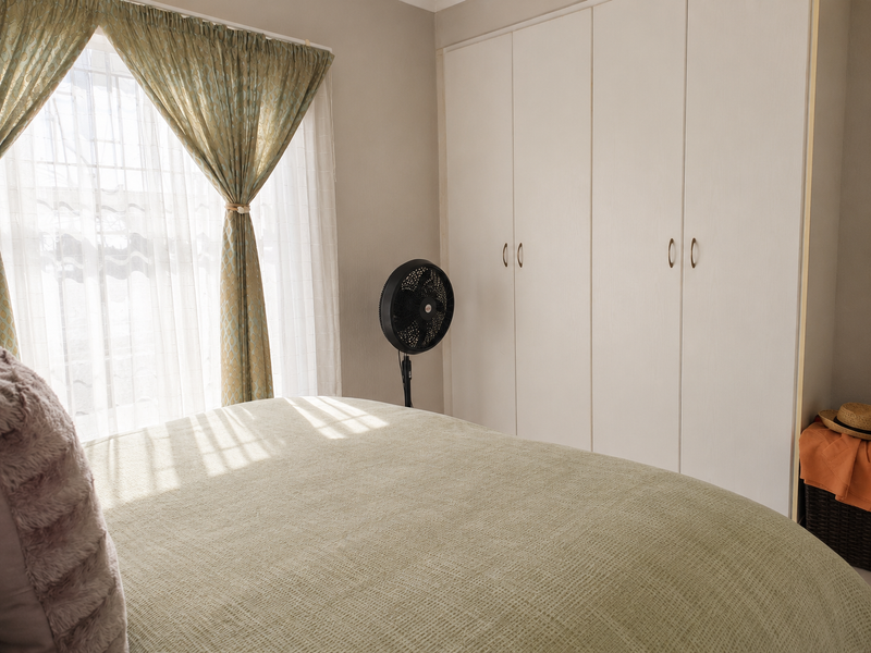 A bedroom featuring neutral walls and functional built-in cupboards, providing ample storage space and natural light through the window.