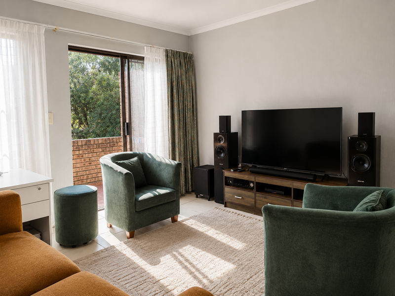 A comfortable living room featuring tiled flooring, cove cornicing, and a sliding glass door providing access to an outdoor balcony area.