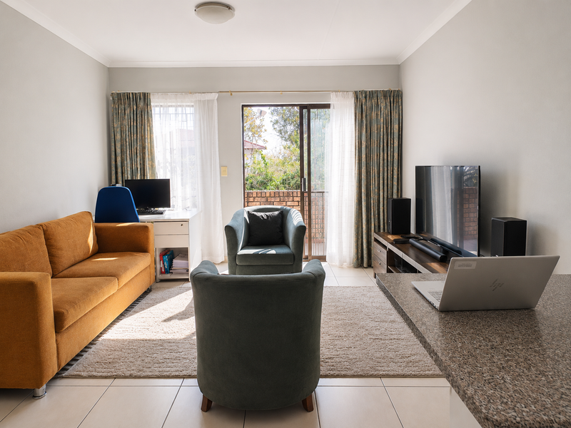 Open-plan living area featuring tiled floors, a granite breakfast bar, and a sliding glass door providing access to an outdoor balcony.