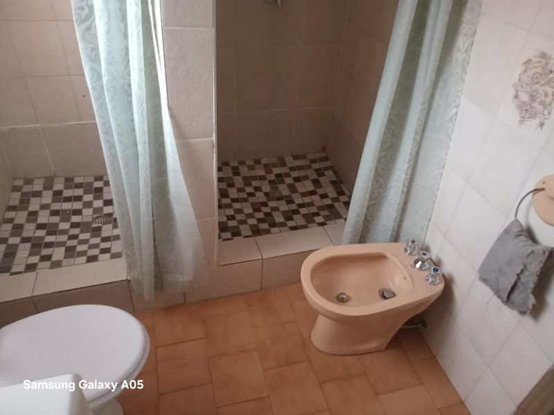 Bathroom featuring dual shower stalls with tiled floors, a bidet, and a toilet. The space requires modernization of fixtures and finishes.