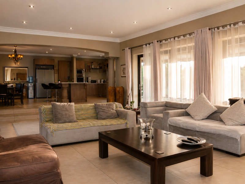 Spacious open-plan living area featuring tiled floors, recessed lighting, and a seamless transition to a well-appointed kitchen with built-in appliances.