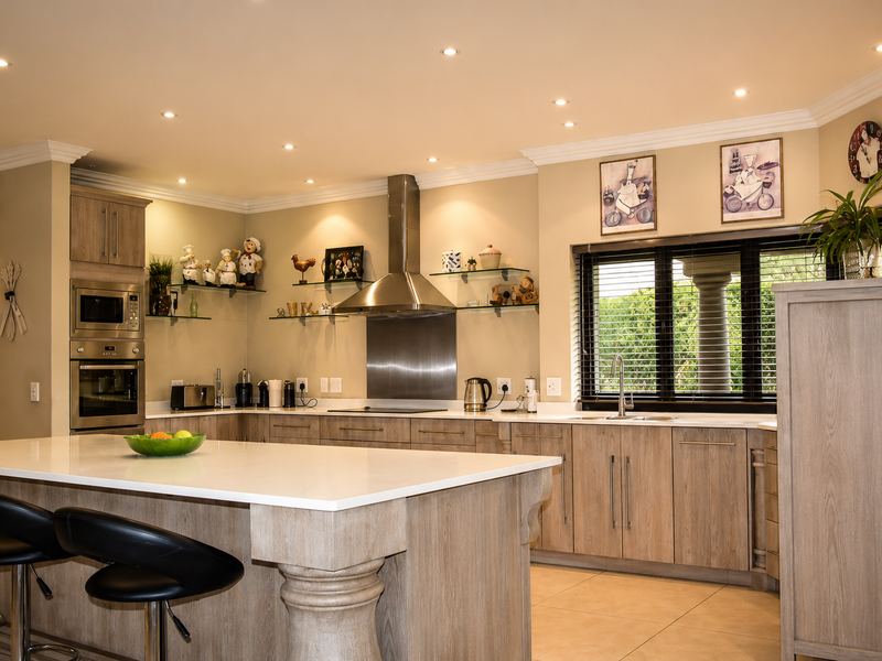 Modern kitchen featuring a large central island, stone countertops, built-in stainless steel appliances, and ample cabinetry with recessed lighting.