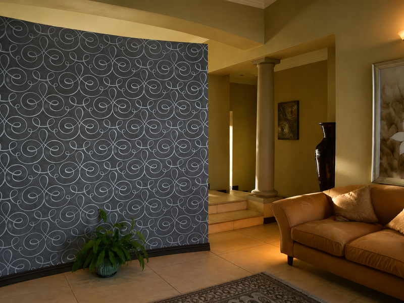 A living area featuring a prominent decorative wallpaper accent wall, tiled flooring, and an architectural column leading to an adjacent space.
