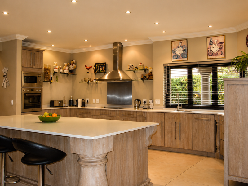 Spacious kitchen featuring a large central island, stone countertops, built-in appliances, and warm recessed lighting, offering a functional and well-maintained culinary space.