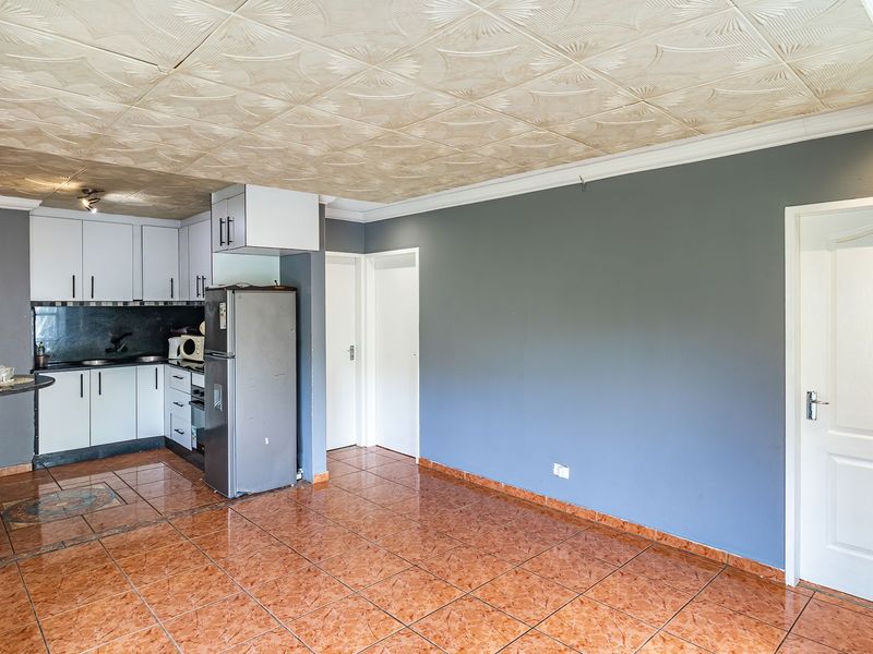 Open plan kitchen and living area featuring tiled flooring, built-in cabinetry with granite countertops, and a breakfast bar.