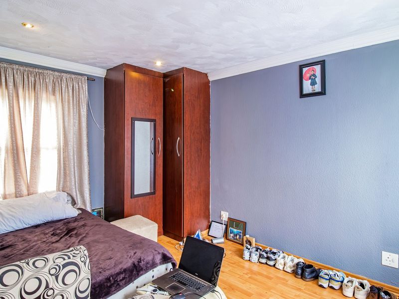 A bedroom featuring laminate flooring, recessed ceiling lighting, and a built-in wooden wardrobe.