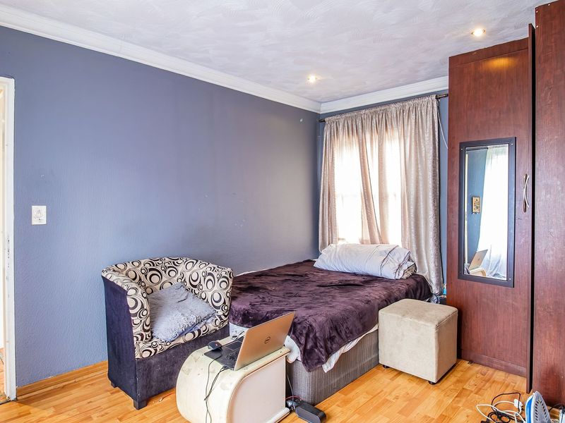 A bedroom featuring laminate flooring, recessed ceiling lighting, and a built-in wooden wardrobe.