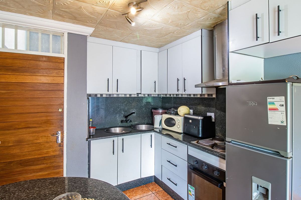 Compact kitchen featuring granite countertops, built-in cabinetry, integrated oven and hob, and a double bowl sink.