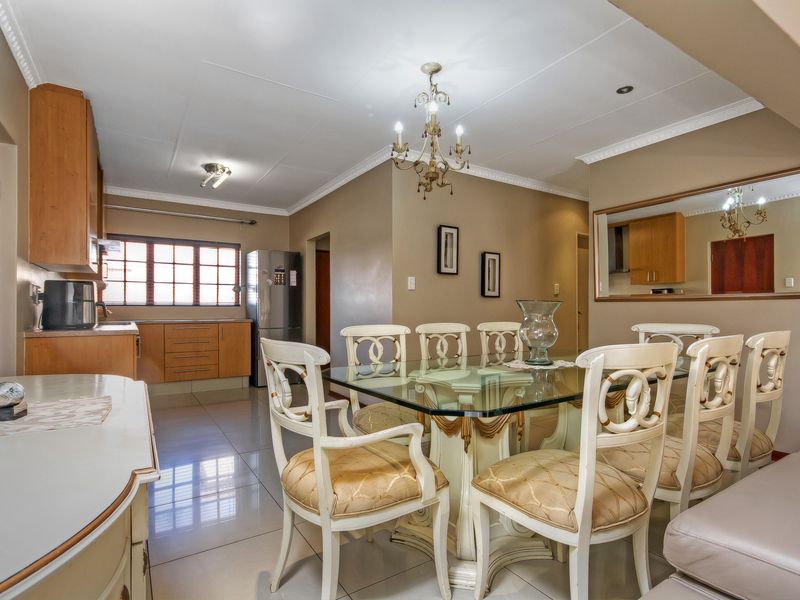 Open plan kitchen and dining area featuring wooden cabinetry, tiled flooring, and decorative crown molding, creating a functional and connected living space.