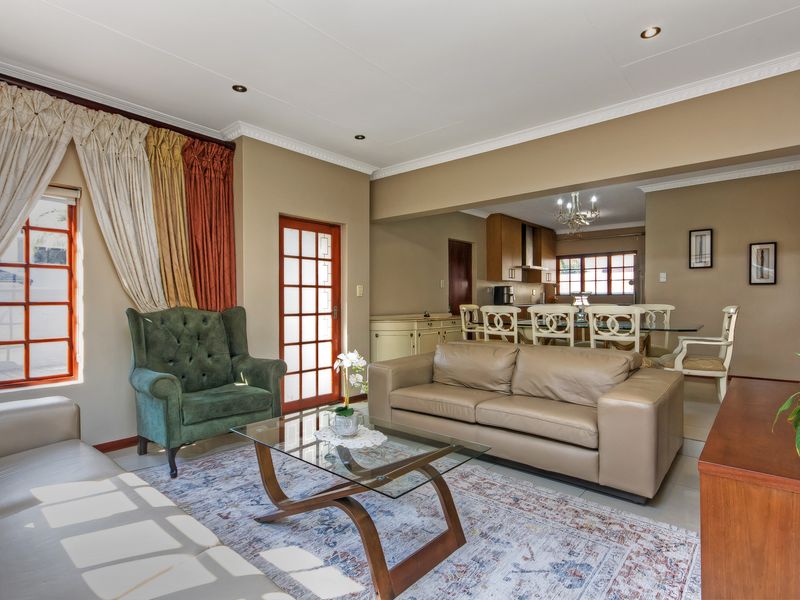 Spacious open-plan living and dining area featuring tiled floors, crown molding, and seamless flow into the adjacent kitchen space.