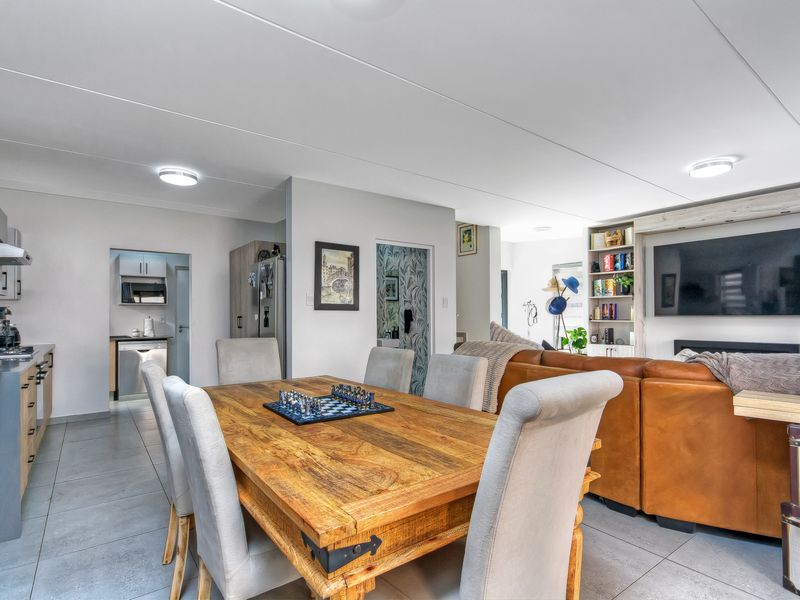 Spacious open-plan living and dining area featuring tiled floors, modern kitchen cabinetry, and a built-in media shelving unit.