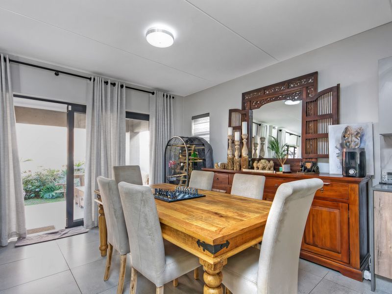 A well-lit dining area featuring tiled flooring and large sliding glass doors that provide direct access to the outdoor patio space.