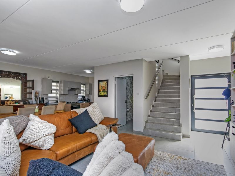 Open-plan living area featuring tiled floors, a modern staircase, built-in shelving, and a seamless transition to the kitchen space.