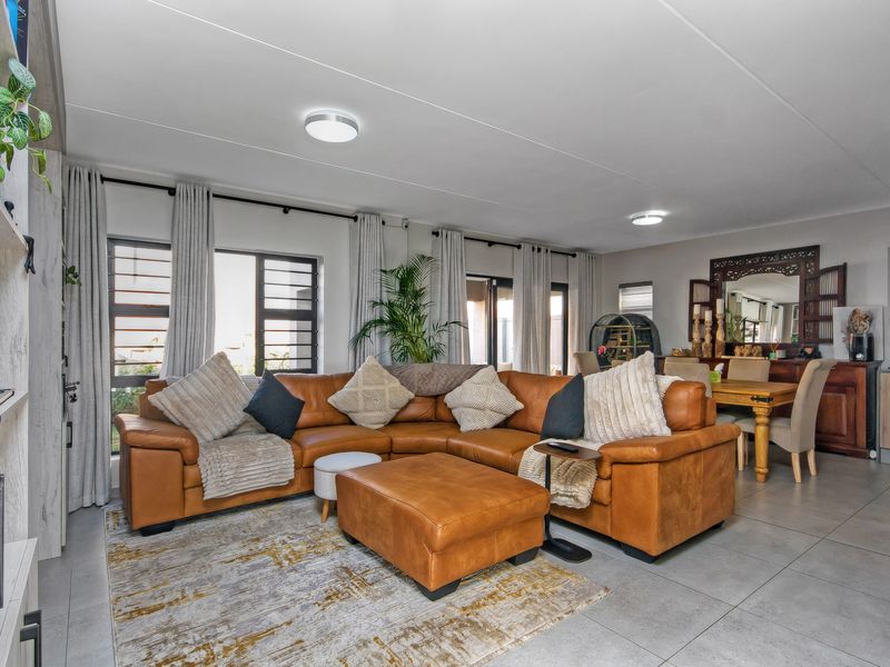 Spacious open-plan living and dining area featuring neutral tiled flooring, large windows with natural light, and modern finishes throughout.