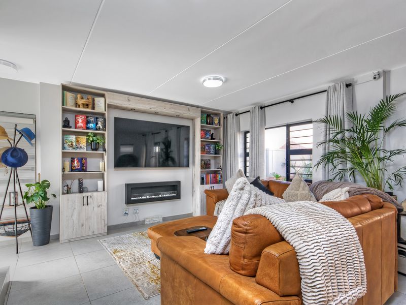 A well-maintained living room featuring custom built-in shelving, an integrated electric fireplace, and large windows providing natural light.