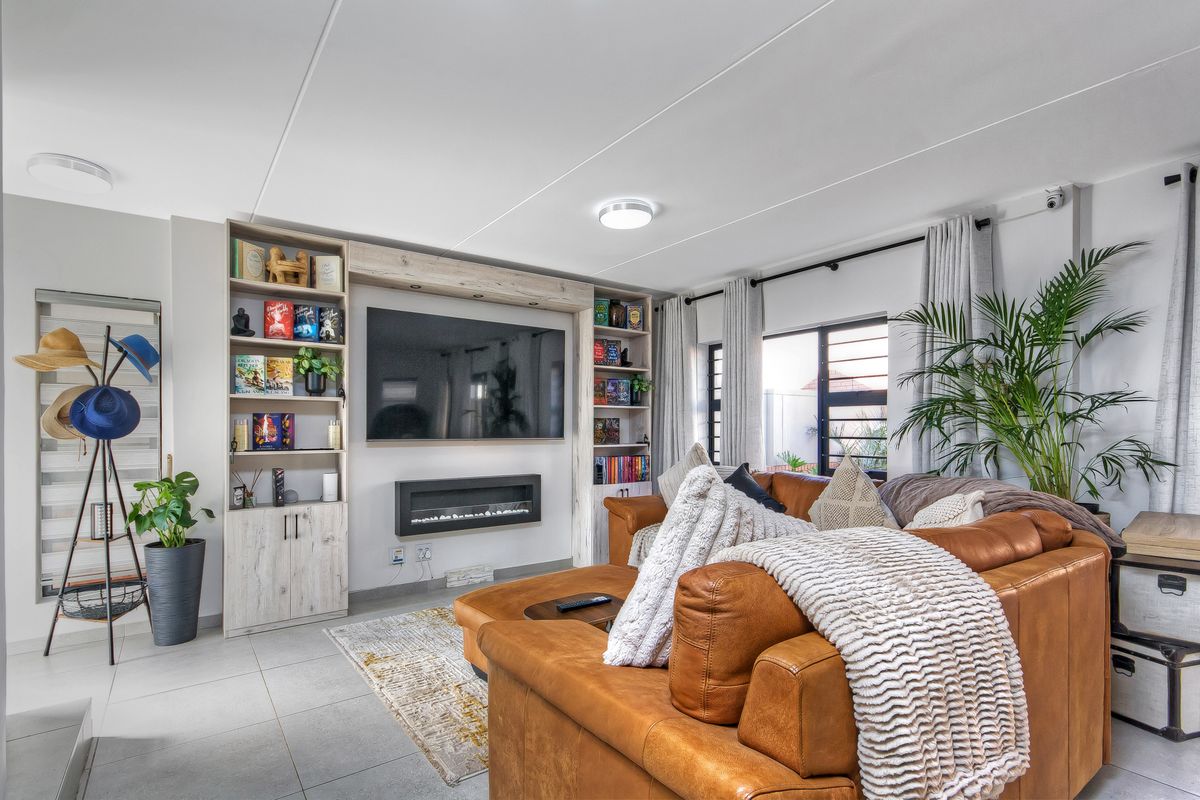 A well-maintained living room featuring custom built-in shelving, an integrated electric fireplace, and large windows providing natural light.