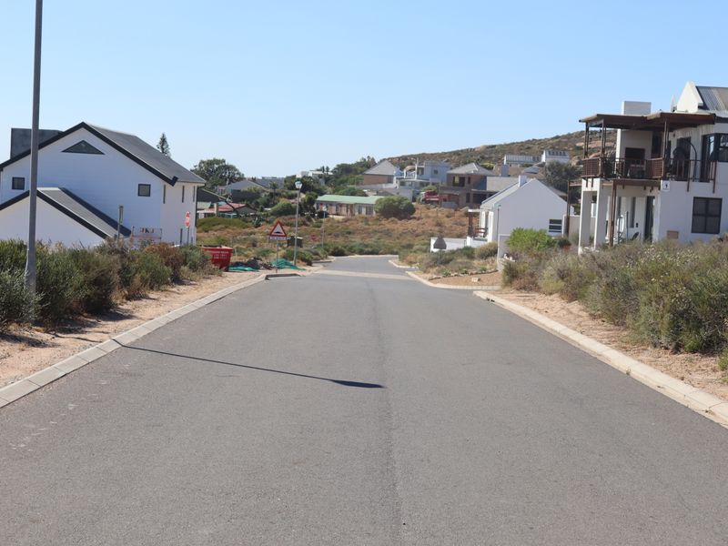 A view looking down a paved residential street in a coastal estate, showing surrounding homes and established infrastructure.