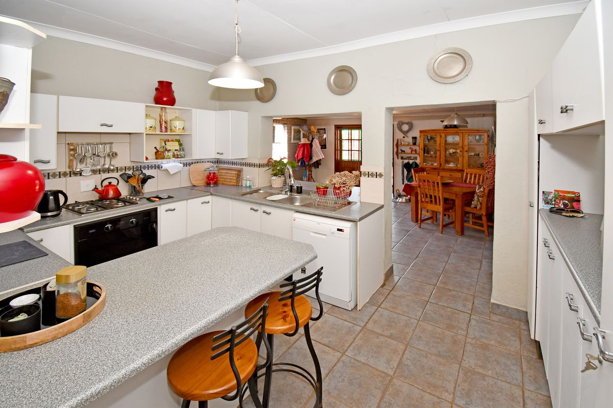 A functional kitchen featuring built-in cabinetry, a gas hob, and a breakfast counter, with an open-plan flow into the adjacent dining area.