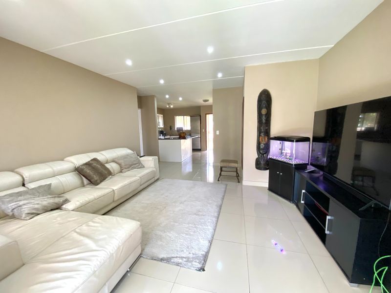 Spacious open-plan living area featuring tiled flooring, recessed downlights, and a seamless transition into the kitchen space.