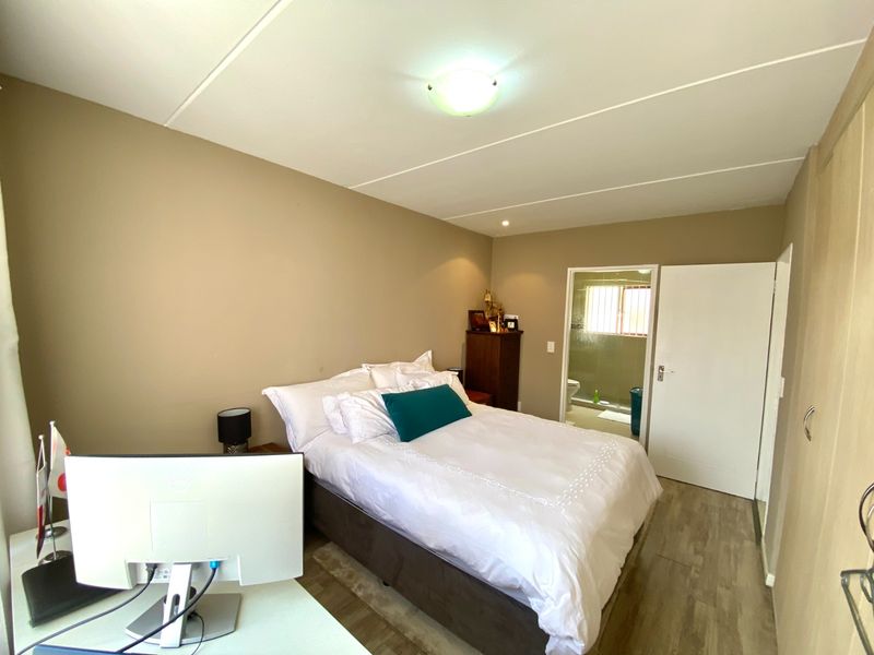 A bedroom featuring laminate flooring, built-in cupboards, and an attached en-suite bathroom.