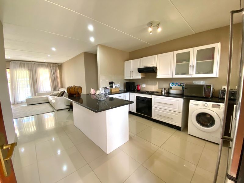 Open-plan kitchen and living area featuring a central island, granite countertops, built-in cabinetry, and tiled flooring throughout.