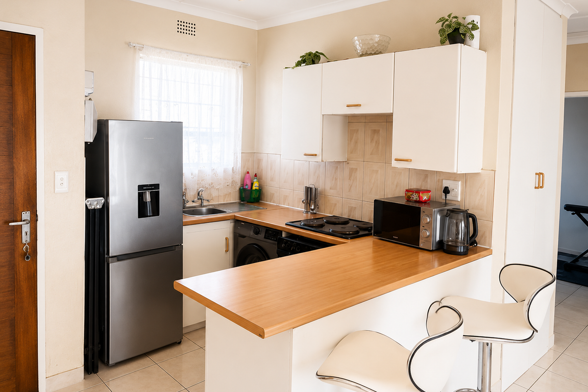 Compact kitchen featuring white cabinetry, laminate countertops, tiled backsplash, and a breakfast bar, providing a functional and efficient cooking and dining space.