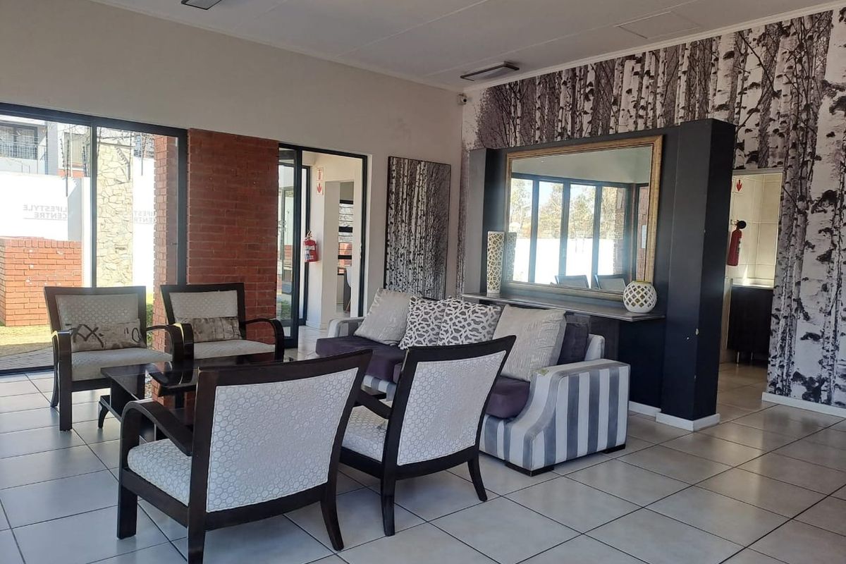 Spacious living area featuring tiled flooring, an exposed brick accent wall, and large sliding glass doors providing natural light and outdoor access.
