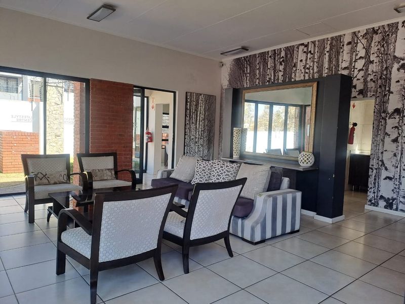 Spacious living area featuring tiled flooring, an exposed brick accent wall, and large sliding glass doors providing natural light and outdoor access.