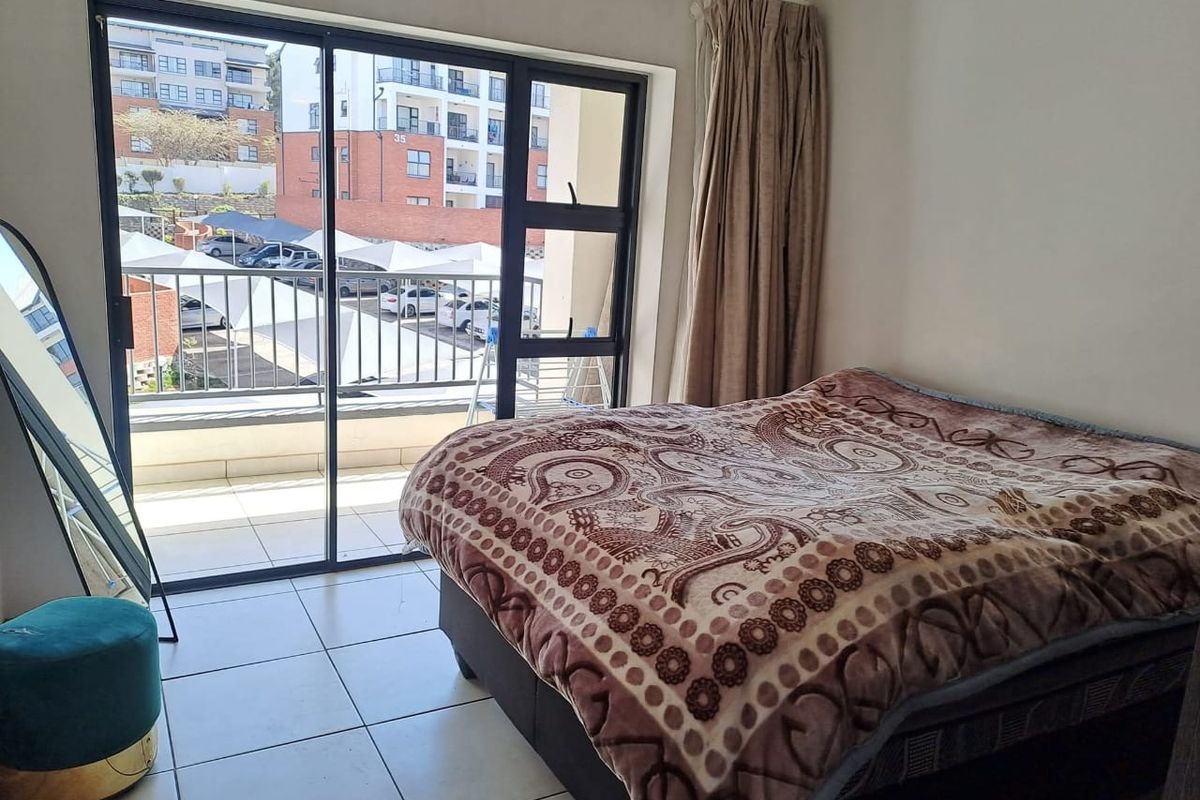 A bedroom featuring tiled flooring and a large sliding glass door providing direct access to a private balcony.