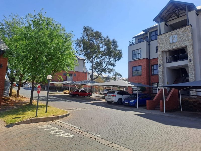 Exterior view of a townhouse complex featuring brick and stone facade, paved driveway, and covered parking bays.