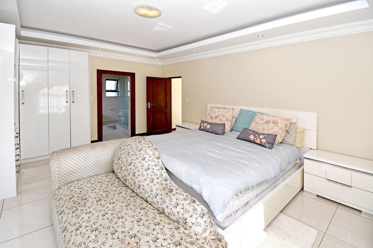 Spacious bedroom featuring glossy tiled flooring, built-in cupboards, and a modern recessed ceiling with integrated lighting.