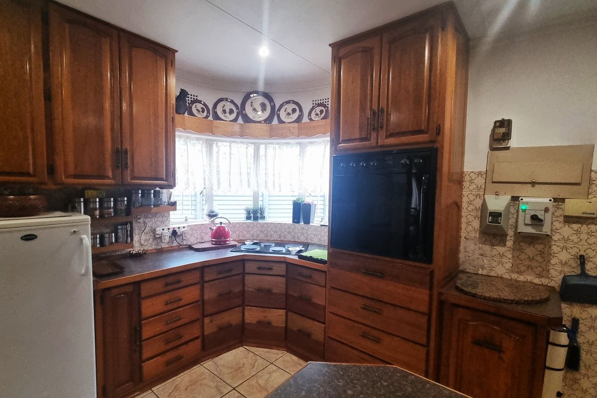A traditional kitchen featuring extensive wooden cabinetry, a built-in oven, electric hob, and tiled backsplash with a functional layout.