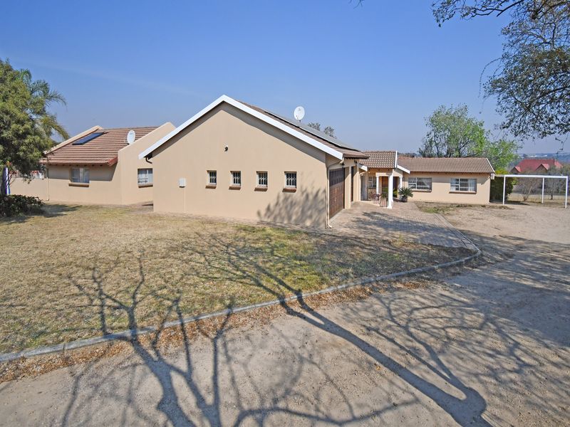 A view of the front elevation of a single-story house featuring a tiled roof, paved driveway, and garage access.