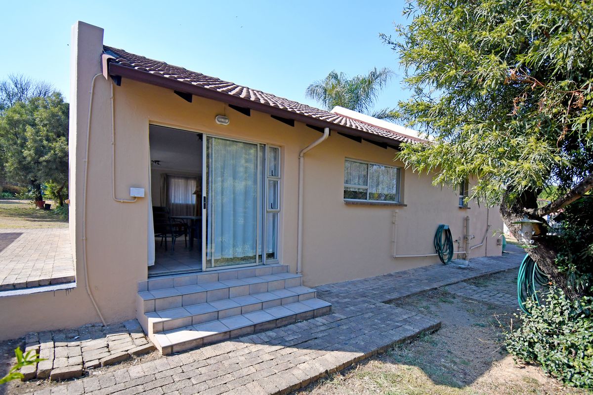 Rear exterior view of the house featuring a tiled roof, sliding glass door access, and a paved walkway leading to the entrance.
