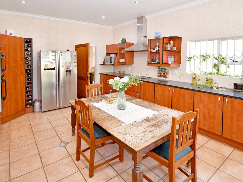 Spacious kitchen featuring wooden cabinetry, granite countertops, stainless steel extractor fan, and tiled flooring with an integrated wine rack.