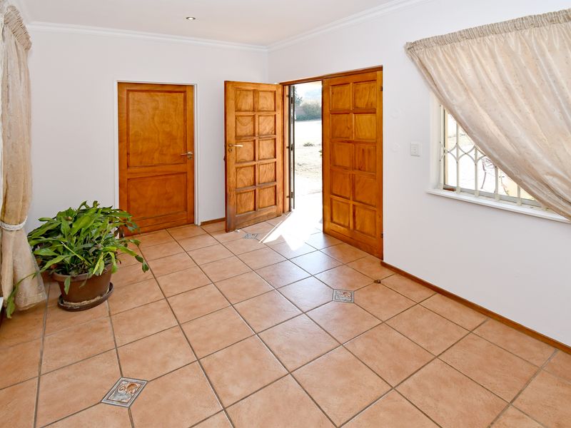 A bright, tiled entrance area featuring wooden panelled doors, decorative floor accents, and direct access to the exterior.