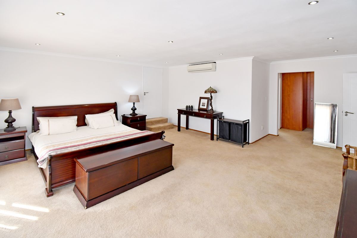 Spacious bedroom featuring neutral walls, carpeted flooring, recessed downlighting, and a wall-mounted split-system air conditioning unit.