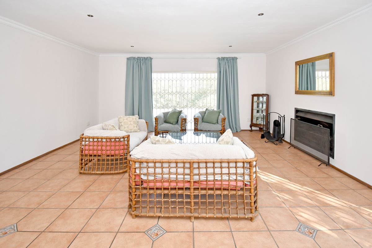 Spacious living room featuring ceramic floor tiles, a built-in fireplace, and large windows with security gates, offering a bright and functional living space.