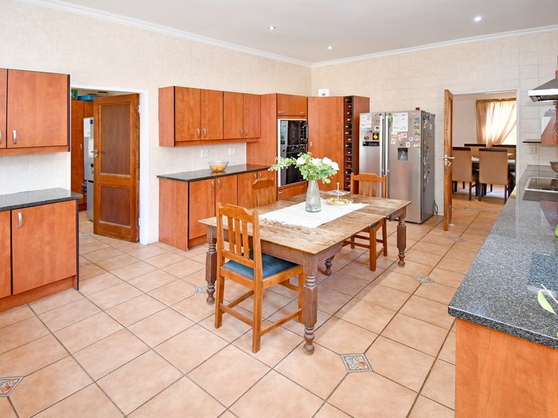 Spacious kitchen featuring granite countertops, built-in oven, extractor fan, and tiled finishes, offering a functional layout with ample storage and workspace.