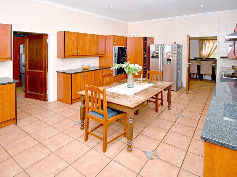 Spacious kitchen featuring wooden cabinetry, granite countertops, built-in oven, and tiled flooring, offering a functional layout with direct access to adjacent living areas.