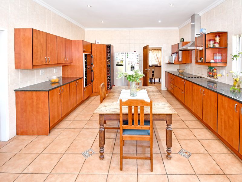 Spacious kitchen featuring wooden cabinetry, granite countertops, built-in oven, extractor fan, and tiled flooring, offering a functional layout with ample storage space.
