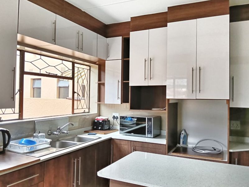 Modern kitchen featuring two-tone cabinetry, stone countertops, a double bowl sink, and ample storage space with a functional layout.