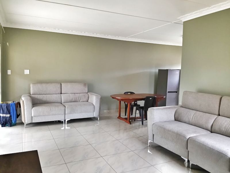 Spacious open-plan living and dining area featuring neutral wall tones, tiled flooring, and decorative ceiling cornices, offering a versatile layout for family living.